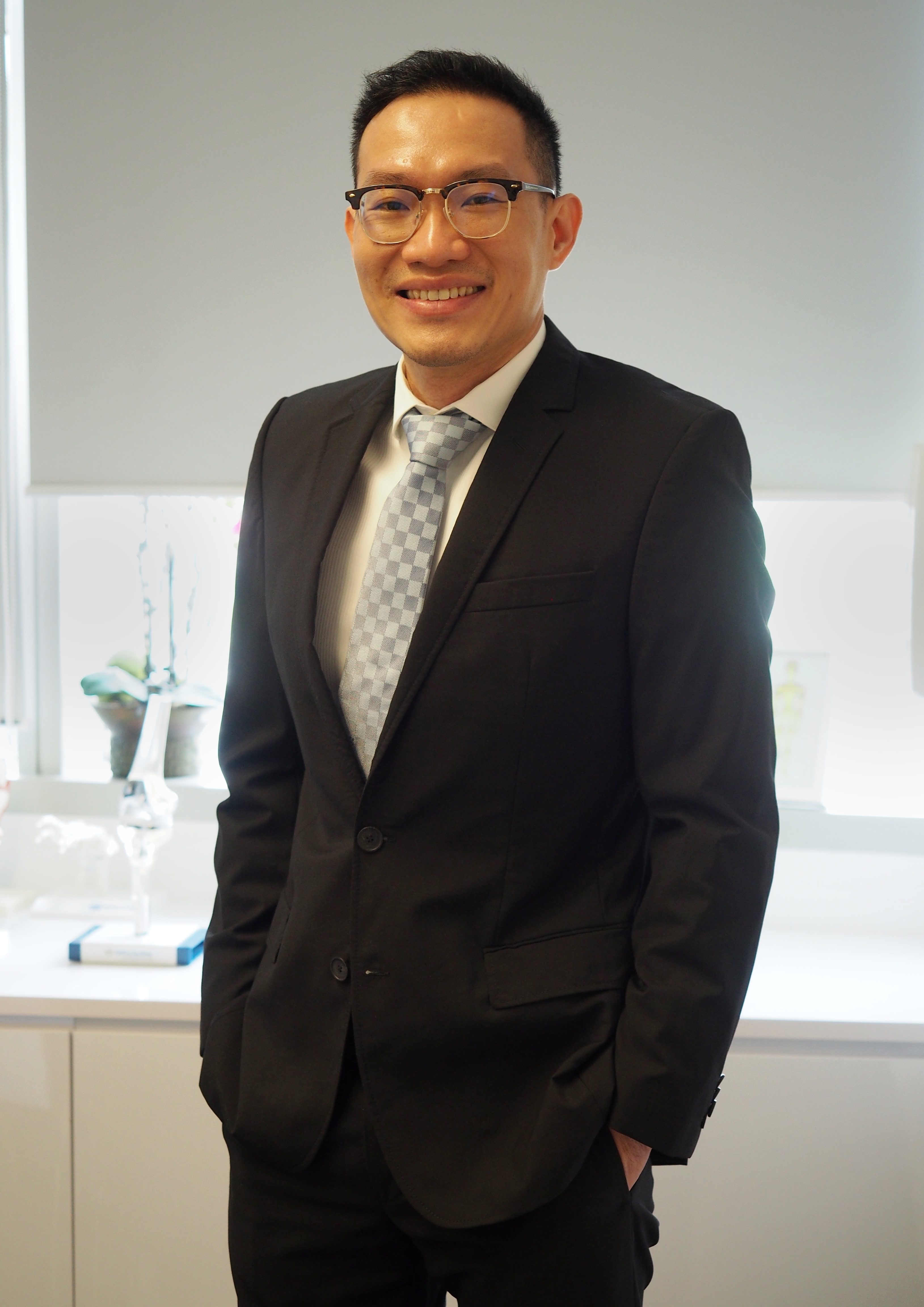 Dr Tan Chyn Hong wearing a suit in clinic